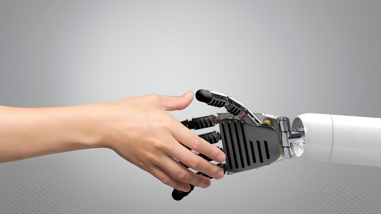 A human hand clasping a robotic hand, the human-plus-AI production model that stays monetizable under YouTube's 2026 rules